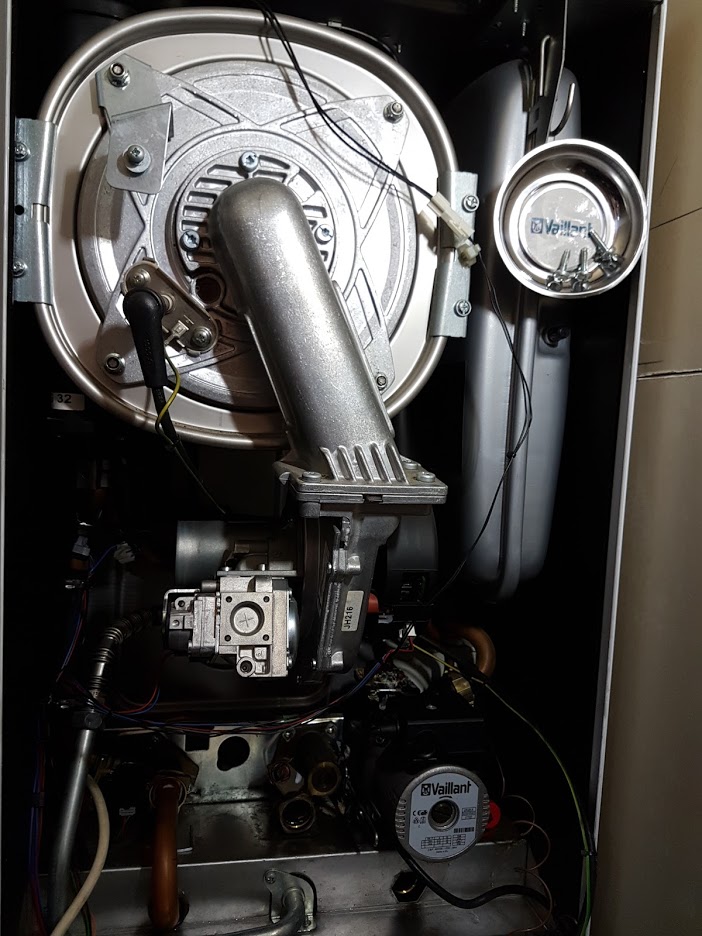 Close-up of the top of a wall-hung boiler, with the fan housing and flue connection