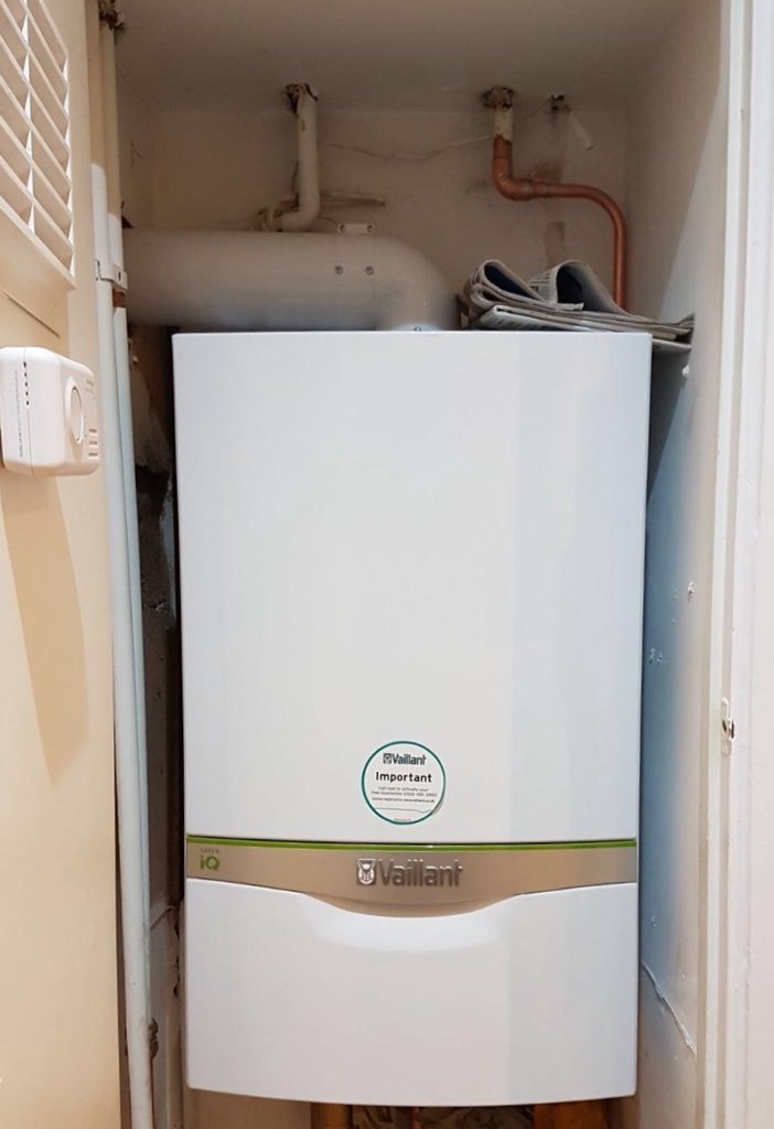 Vaillant ecoTEC exclusive 835 Green iQ combi on a white wall, with a vertical flue, magnetic filter, de-aerator, and copper pipework below