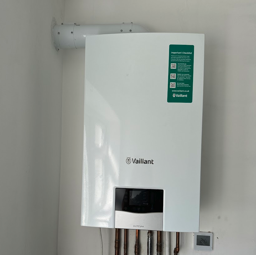 Vaillant ecoTEC plus combi boiler on a wall, with a horizontal flue and copper pipes underneath